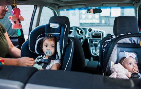 kids in the backseat of a car in different sized car seats Target care seat trade in event 2024