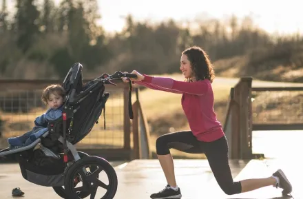 Mom young child in running stroller doing a lunge for exercise on best paths and trails for kids and strollers around Seattle and the Eastside