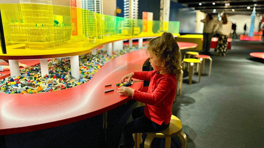 Young girl stacking Lego bricks at the interactive Towers of Tomorrow exhibit