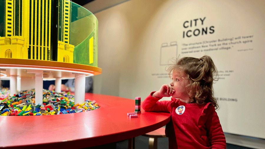 Young girl looks inspired by the Lego display at MOHAI while building her own tower