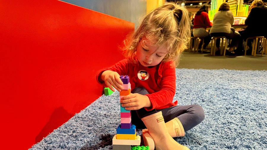 Young girl playing with Duplo blocks on the carpeted area in the Duplo section of the Lego exhibit at MOHAI