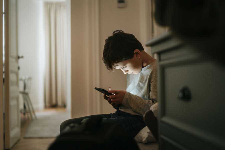 "A boy sitting alone looking at a phone the anxious generation"