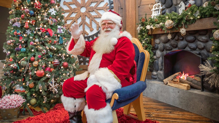 Santa waves from his chair at Snowflake Lane Factory Santa photo set in Bellevue