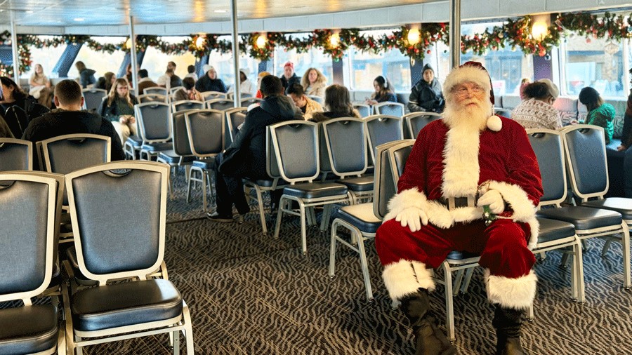 Santa sitting on a chair on the first level of the Argosy Christmas Ship greeting families