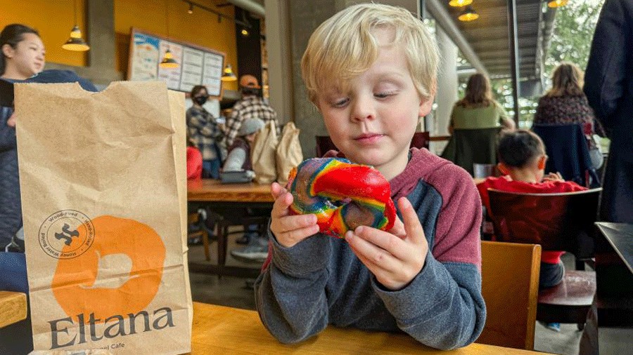 young boy enjoying a rainbow bagel at Eltana in Seattle