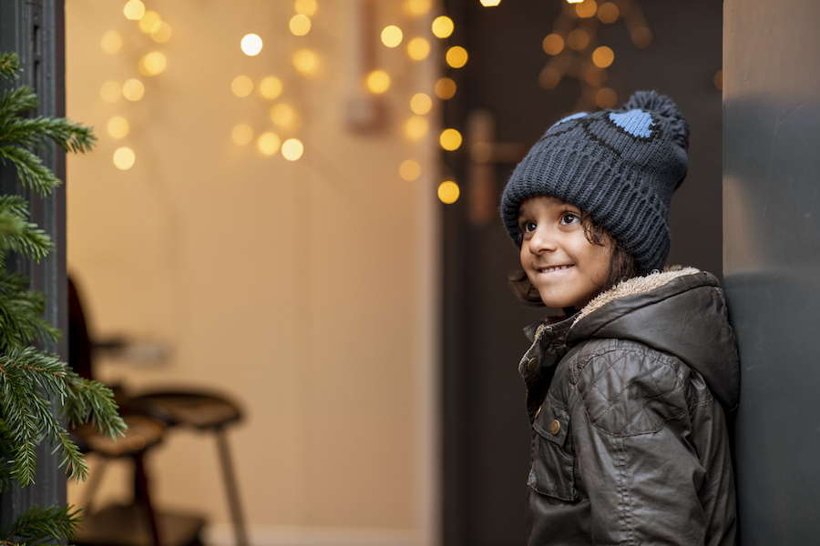 child smiling in a candid photo with christmas lights in the background