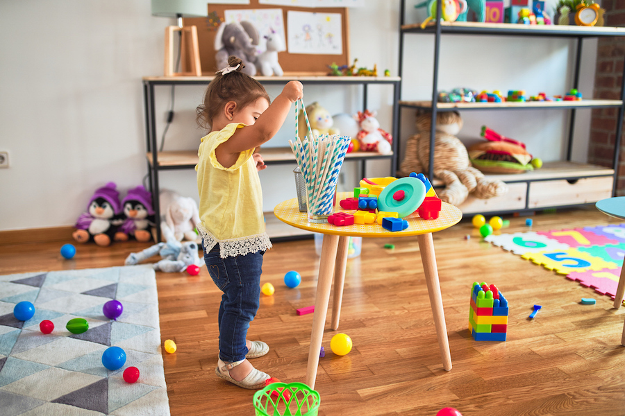 child in a messy playroom filled with many toys