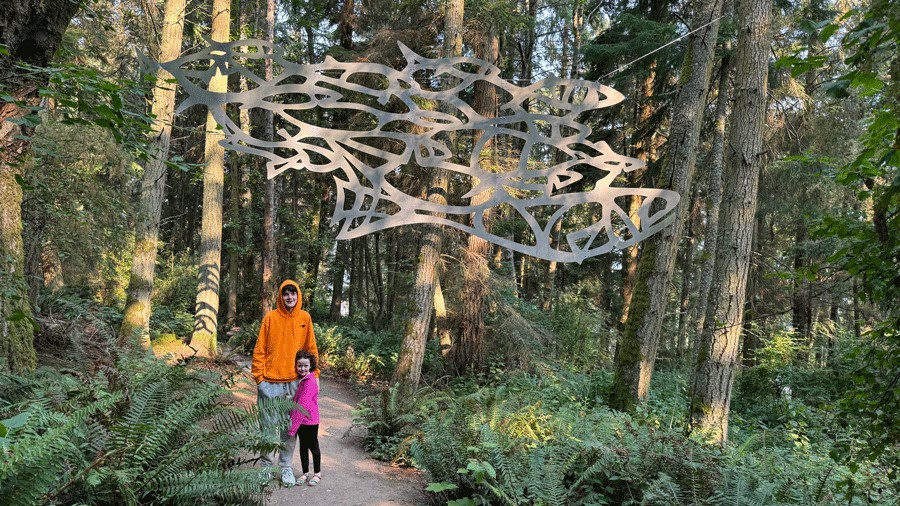 Kids in front of a silver sculpture in a forest on Whidbey Island, a short day trip from Seattle