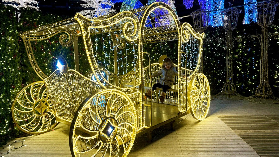 young girl posing inside a lit carriage at Enchant Christmas, a Seattle holiday attraction