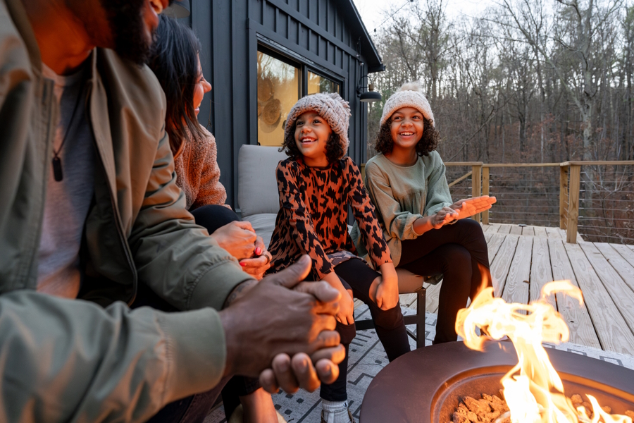 family sitting by a firepit outside at a cabin in the winter