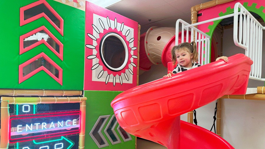 young girl sliding down the pink slide at Little Pandas Play Cafe, a Seattle-area indoor birthday party venue