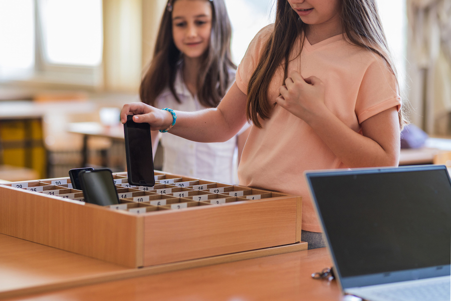 kids putting cell phones in a classroom "parking lot" holder