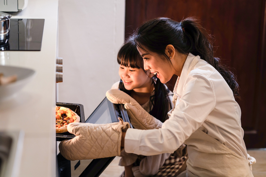 mom and child pulling a homemade pizza from the oven