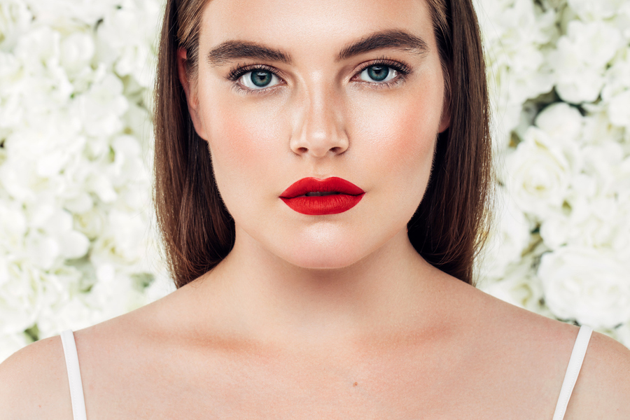 woman wearing red lipstick in front of white flowers