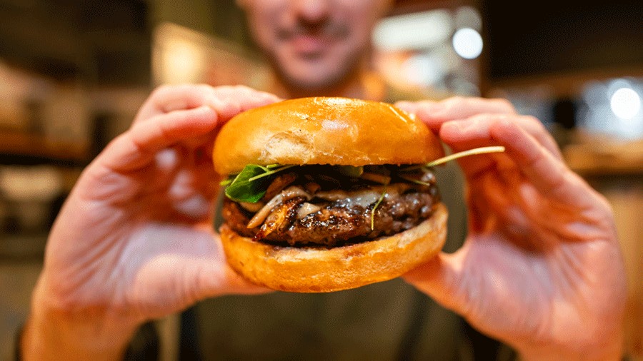 person holding a burger from Uneedaburger, a Seattle comfort food restaurant with burgers and cheese curds