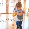 Adorable toddler plays with a plastic cup at preschool