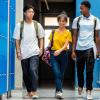 Three high school students walking down a school hallway