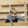 child plays in a Montessori playroom featuring low shelves and simple toys