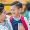 Boy with a red backpack smiling with is father because he's overcome school anxiety