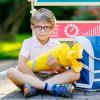 boy sitting on the sidewalk with a blue backpack holding a yellow back-to-school Schultuete 