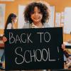 Young girl on first day of school holding up a back-to-school sign