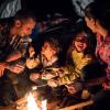 Families around a campfire roasting marshmallows and playing a campfire game