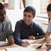 Teenagers sitting around a table with a teen girl as the leader