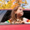 Girl with her head out the window of a car looking at fall leaves on a scenic drive in the Pacific Northwest