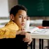 elementary-age student in an empty classroom looking back at the camera