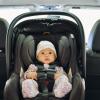 A baby in a rear-facing, safety-stickered car seat in the backseat of a car