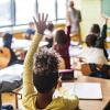 Classroom at school full of students, several raising their hands to answer a question