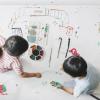 Two siblings painting on butcher paper together