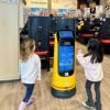 A robot greets two kids at Kura Sushi, a Seattle-area robot restaurant with a sushi conveyor belt