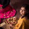 Girl celebrates Diwali Festival of Lights Around Seattle with diya and rangoli.