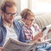 dad and son reading current events in the newspaper