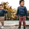 Two little kids playing in a puddle at a park on a rainy day