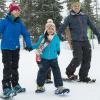 Twp parents and kids snowshoeing in the winter on a family adventure