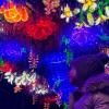 young girl looking up at "Boulevard of Blossoms" a WildLanterns display of hanging flowers at the west entrance of Woodland Park Zoo in Seattle