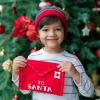 child under a Christmas tree holding a letter for Santa