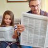 Dad and daughter reading the newspaper together