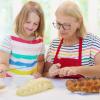 child and grandmother baking challah bread together