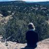 girl sitting and looking out at trees over a ravine. Neurodiverse family travel 