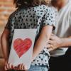 child holding a valentine behind their back for their parent