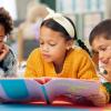 three kids on the floor reading a book together