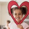 little girl holding a heart shape around her head