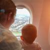 mom and baby on an airplane looking out the window and a city below