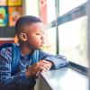 a young student looks out the window at school pensively