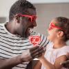 A dad and daughter wearing heart sunglasses, a useful valentine gift for kids while exchanging a red heart