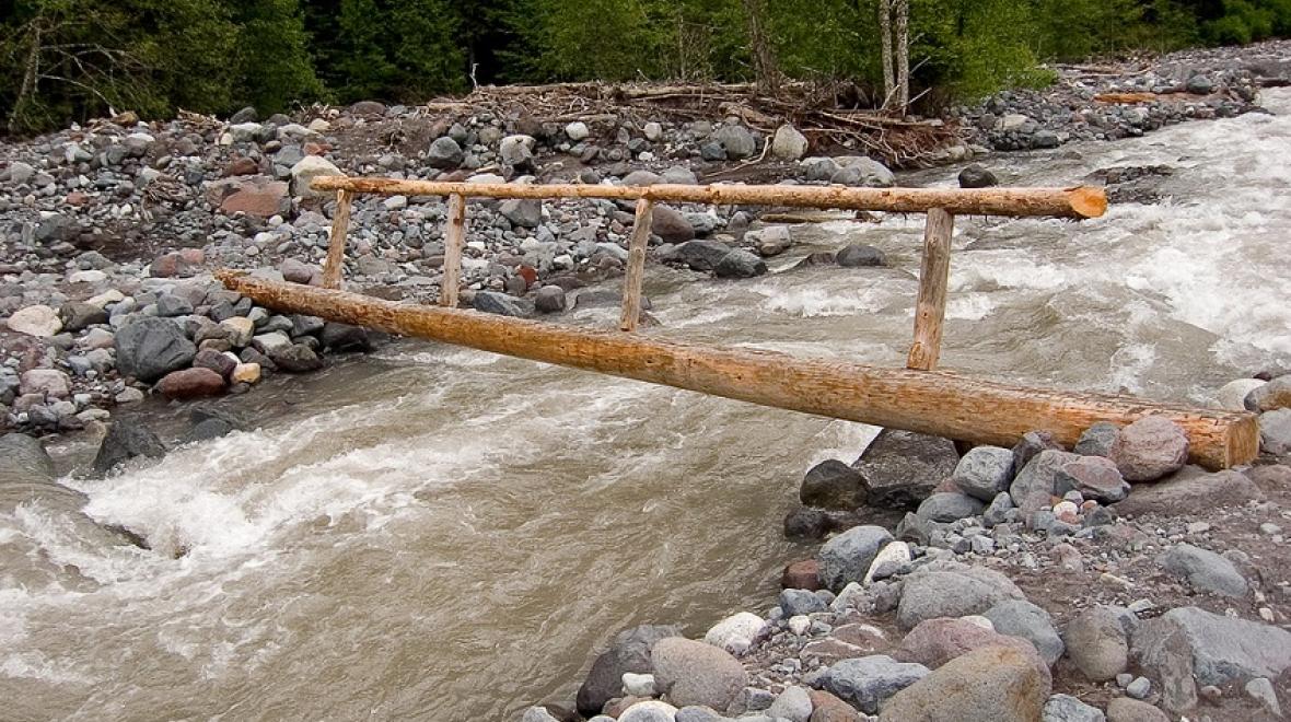 A log footbridge crosses the Carbon River at Mount Rainier on the way to Carter Falls