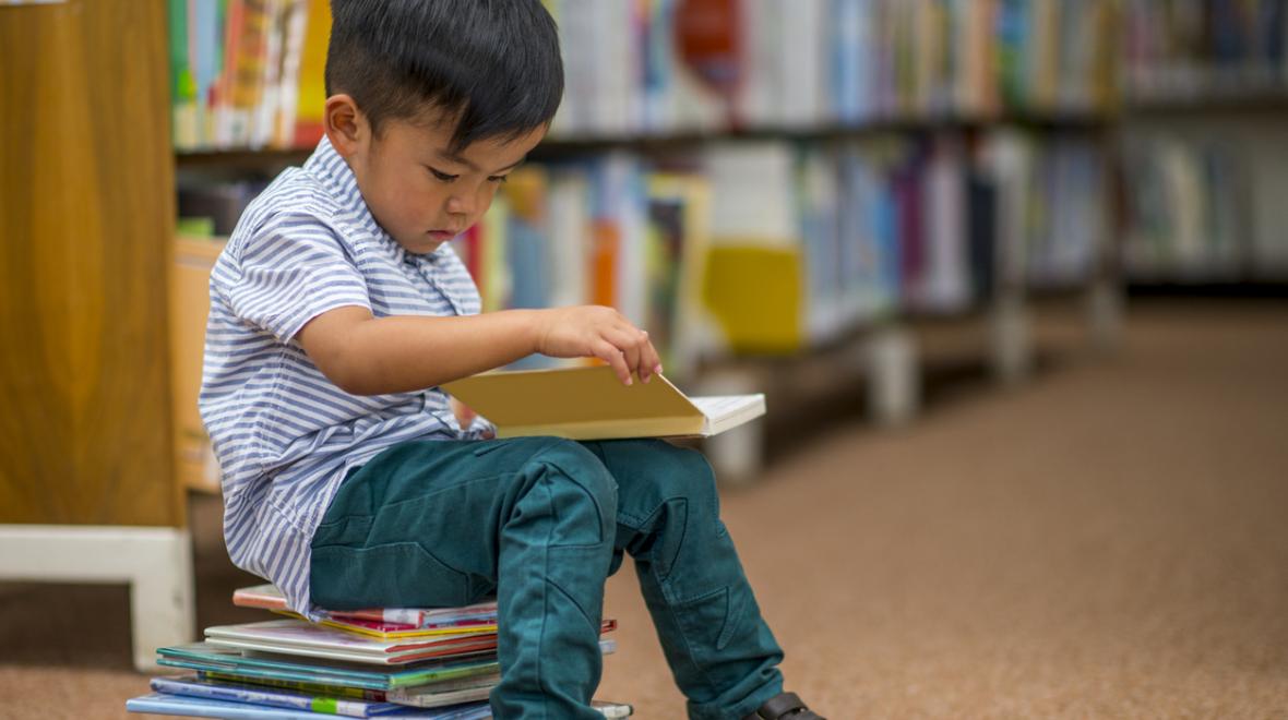 A young boy reads books at a public library